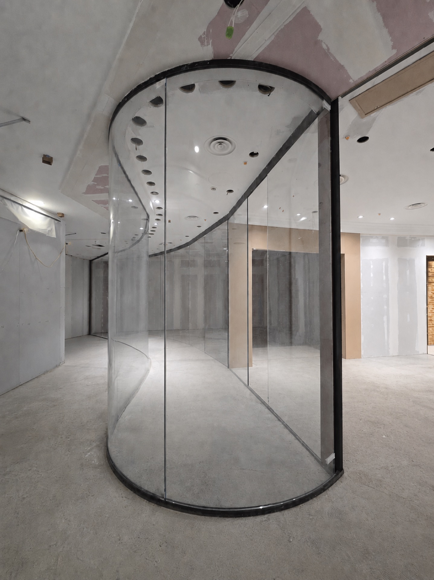 Curved structural glass panel standing in an empty retail unit during shopfit