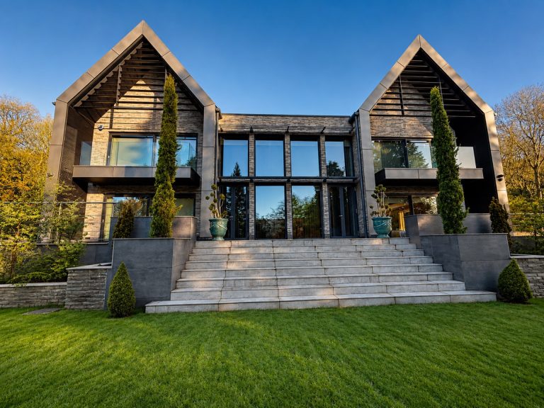 Modern twin-gable home in Ilkley with large-format dark-framed aluminium glazing and stone steps to the garden