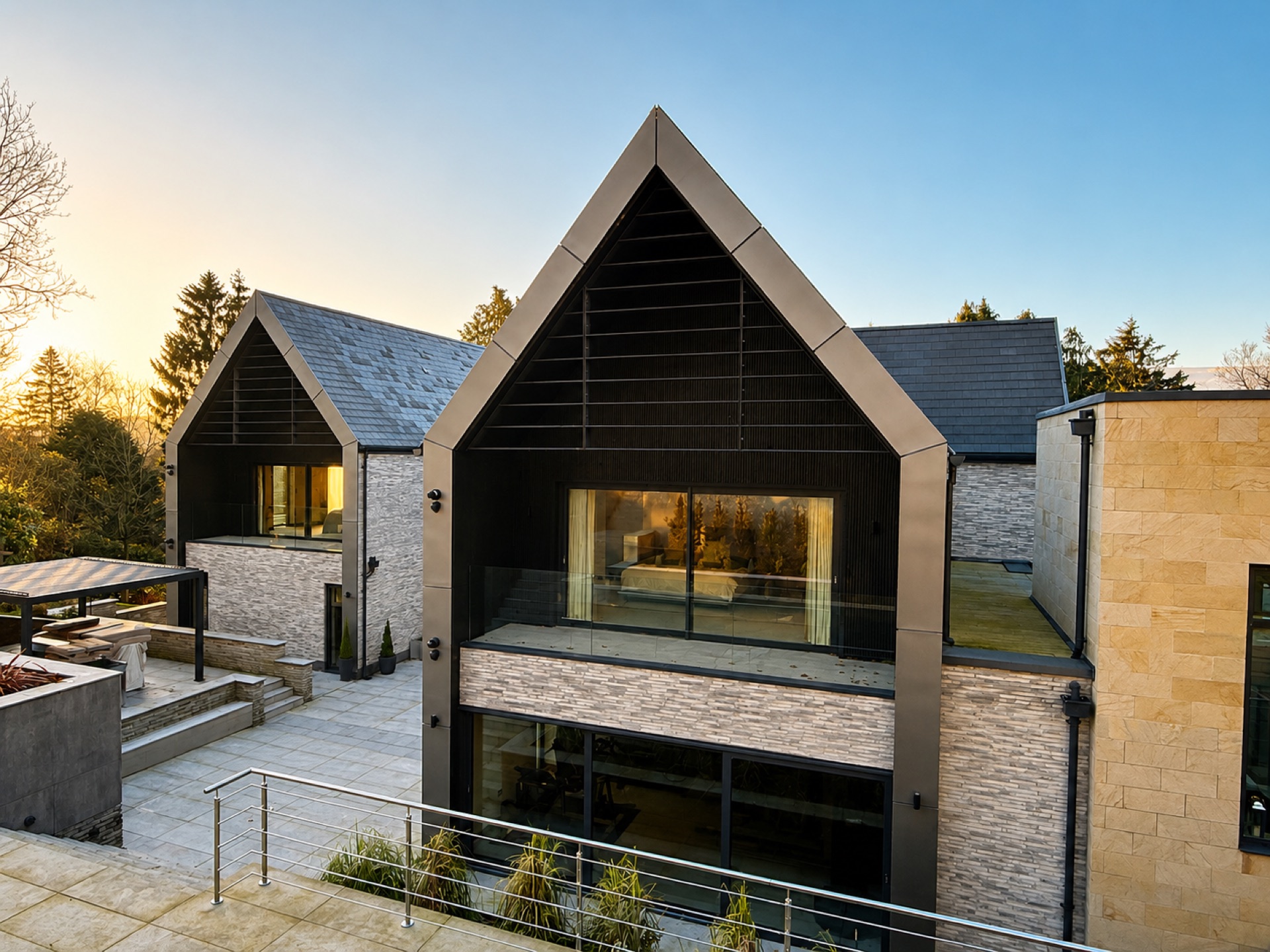 Dusk view of an Ilkley home with dark-clad gable, frameless glass balcony balustrade and floor-to-ceiling aluminium glazing