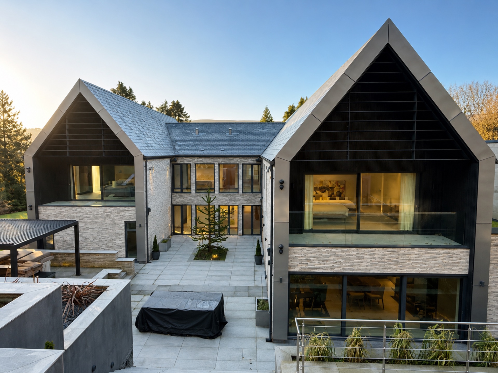 Contemporary Ilkley house at dusk with lit interiors, Schüco lift-and-slide doors and frameless glass balustrade