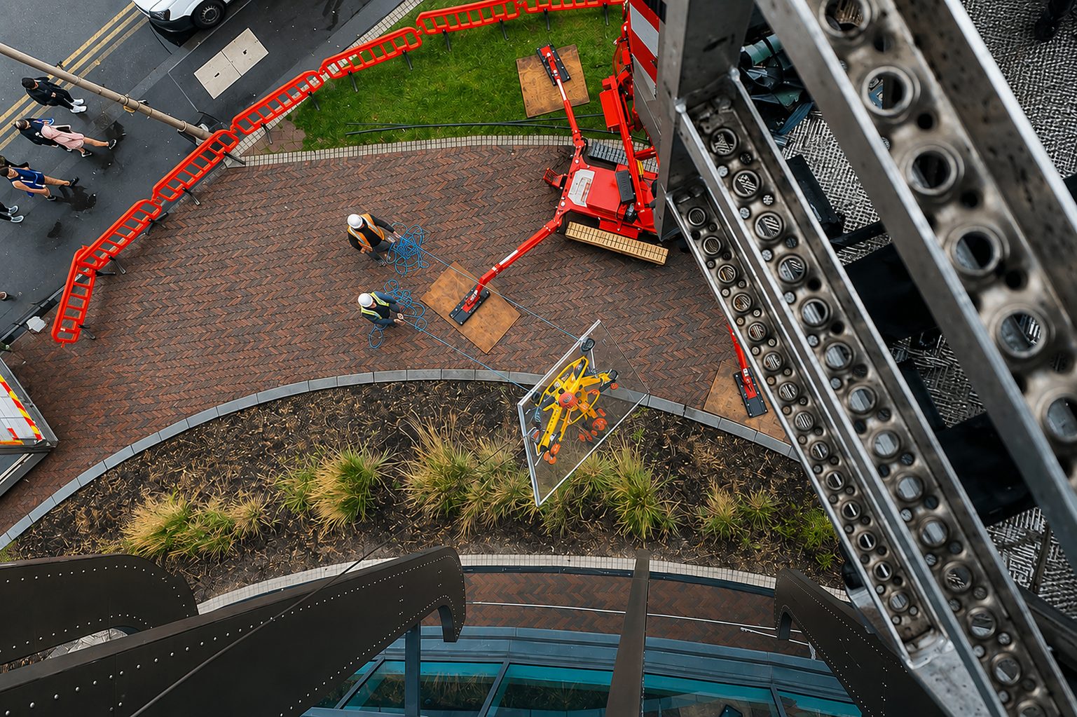 Overhead view of a crane lifting a large glass panel into position on an AGS installation
