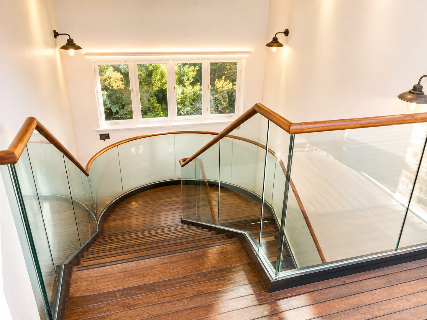 Curved frameless glass balustrade with oak handrail on a staircase