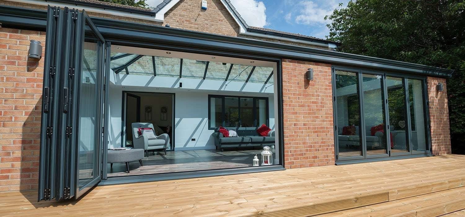 Anthracite aluminium bifolding doors folded fully open onto timber decking