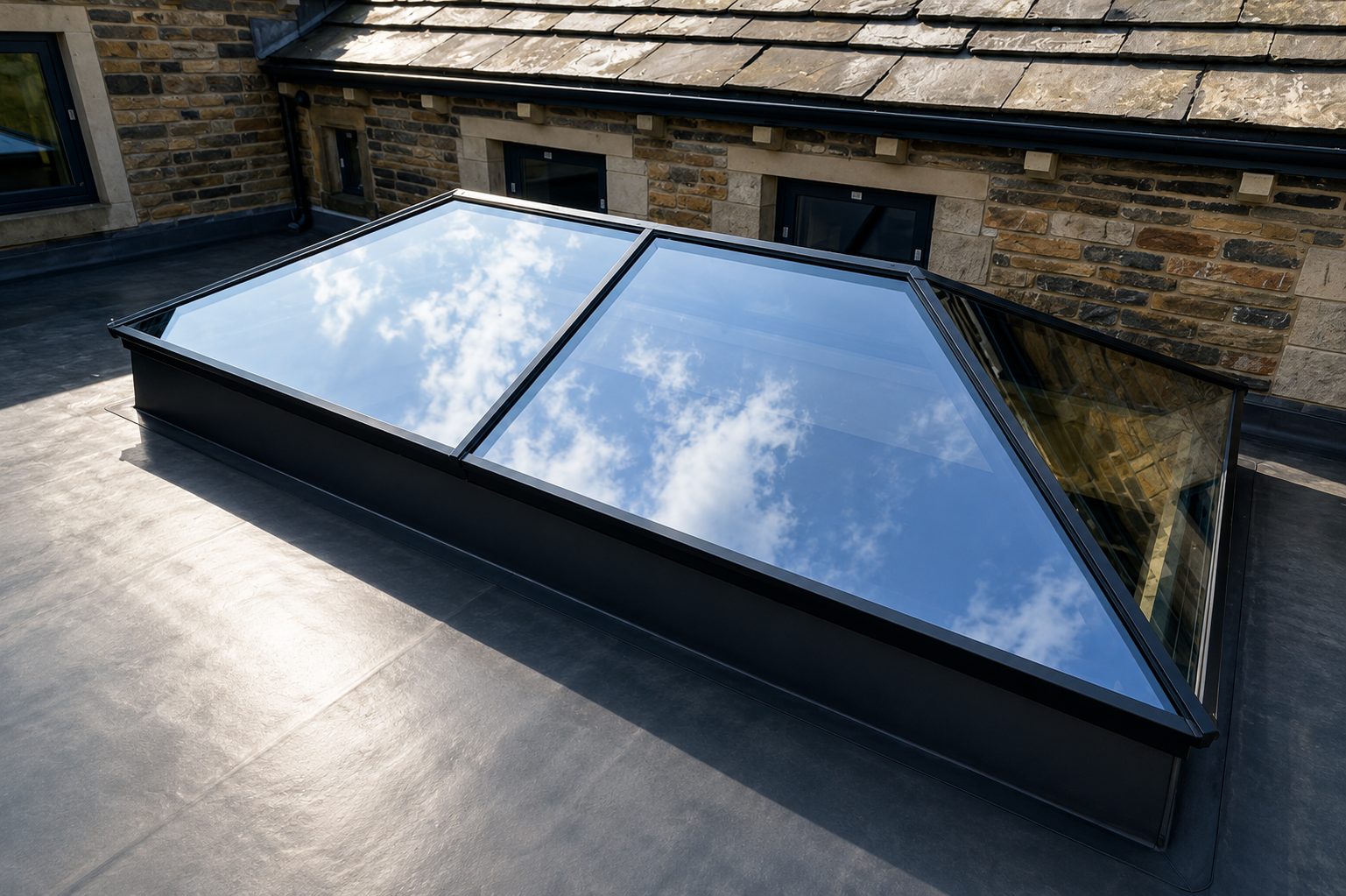 Aluminium roof lantern on a flat roof between stone walls