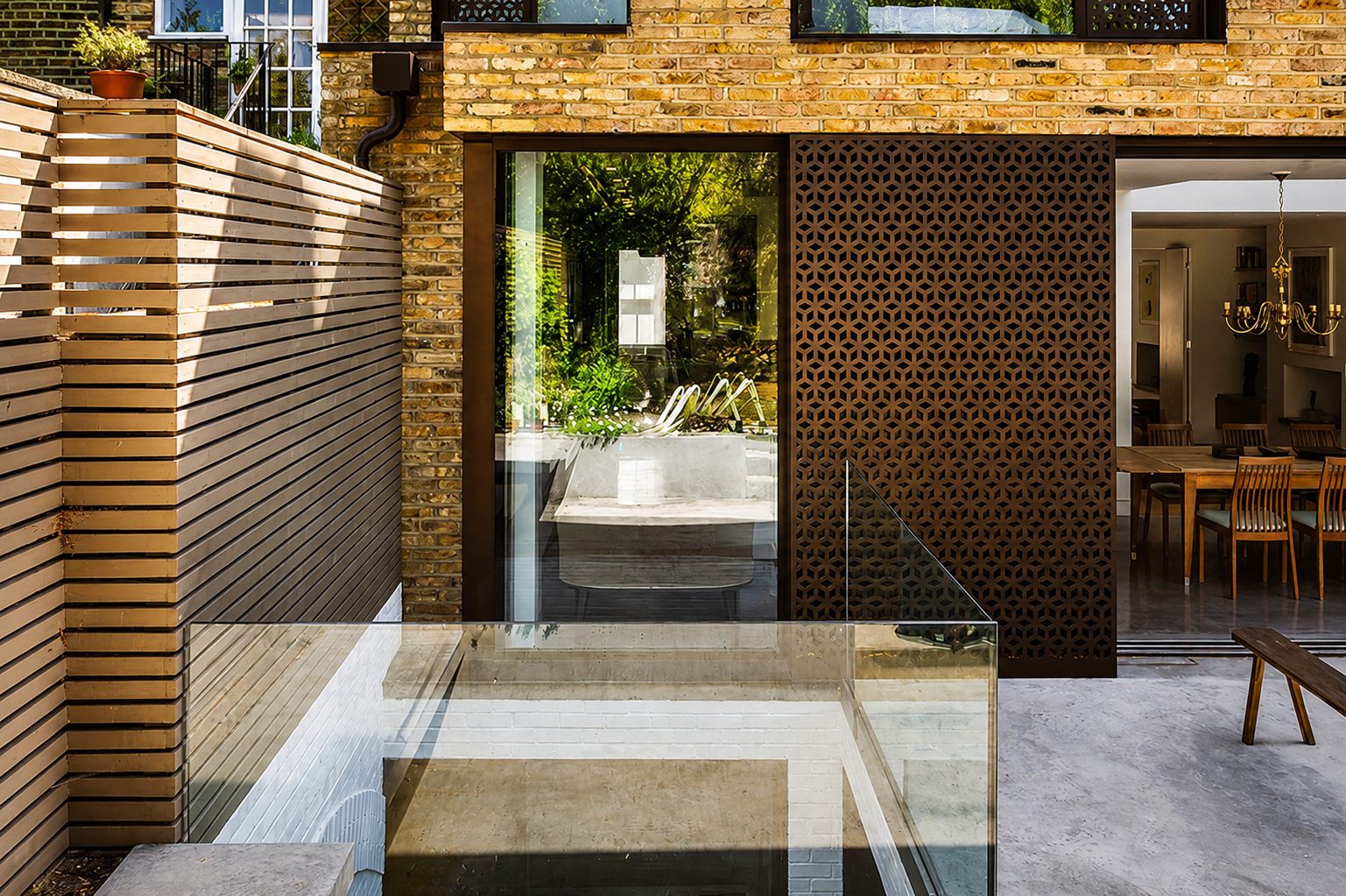 Structural glass floor and balustrade over a lightwell beside a brick extension