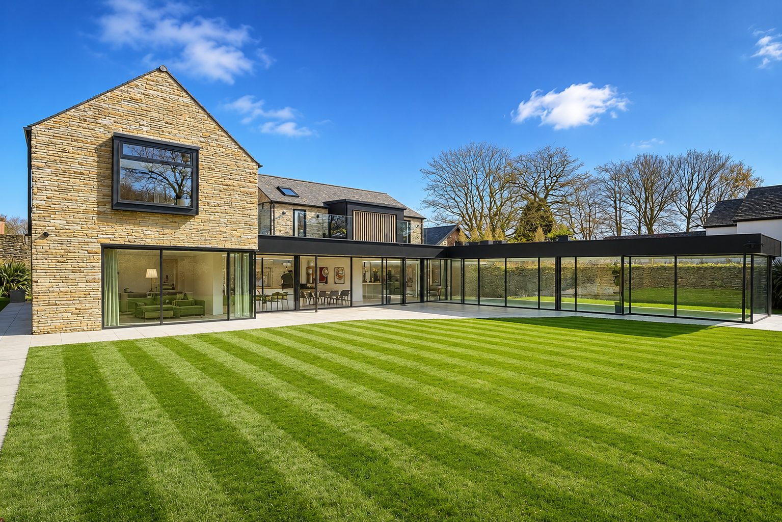 Contemporary stone house with a single-storey glazed link and slim aluminium framing