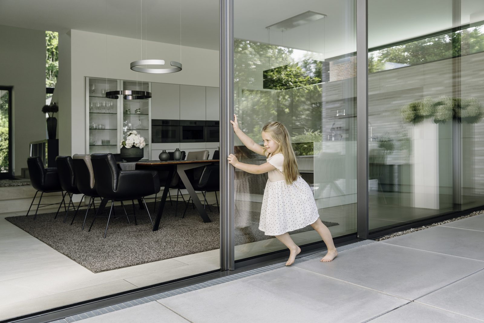 Solarlux cero minimal-frame sliding glass door being opened from a dining room